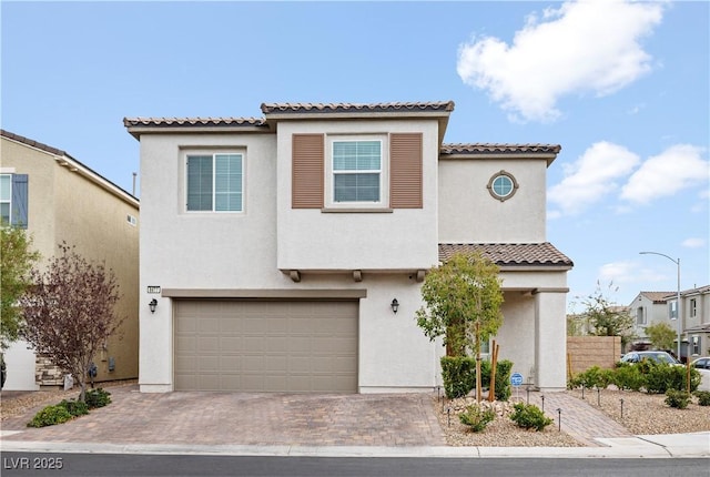 view of front of home featuring decorative driveway, an attached garage, and stucco siding