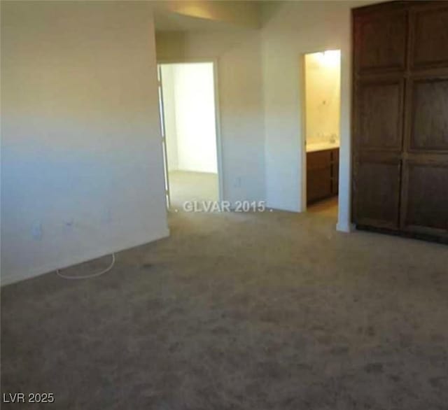 unfurnished bedroom featuring ensuite bath and light colored carpet