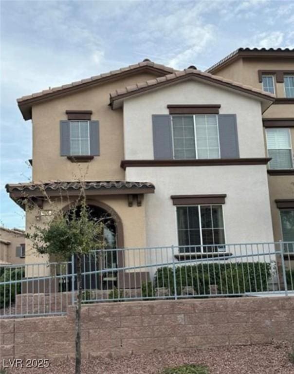 view of front of house with a tiled roof, fence, and stucco siding