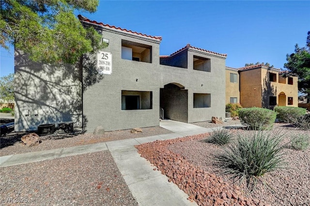 view of front of home featuring central air condition unit, a tiled roof, and stucco siding