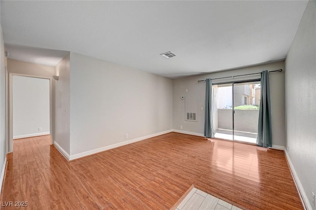 spare room featuring baseboards, visible vents, and wood finished floors