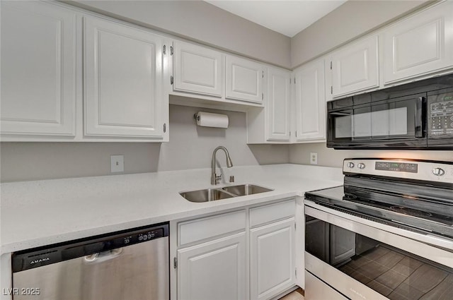 kitchen with appliances with stainless steel finishes, white cabinets, light countertops, and a sink