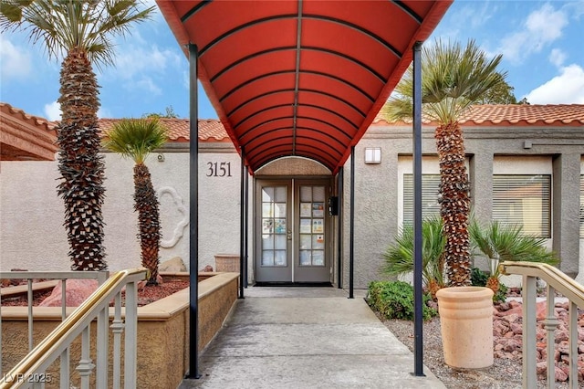 entrance to property featuring a tiled roof and stucco siding