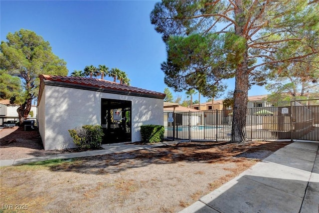 view of front facade featuring a tiled roof, fence, and stucco siding