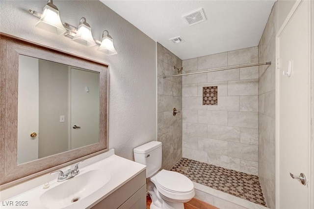 full bathroom with toilet, visible vents, and a tile shower