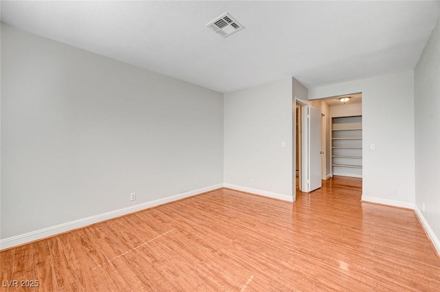 spare room featuring visible vents, light wood-style flooring, and baseboards