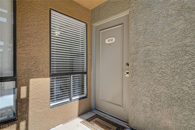 doorway to property featuring stucco siding