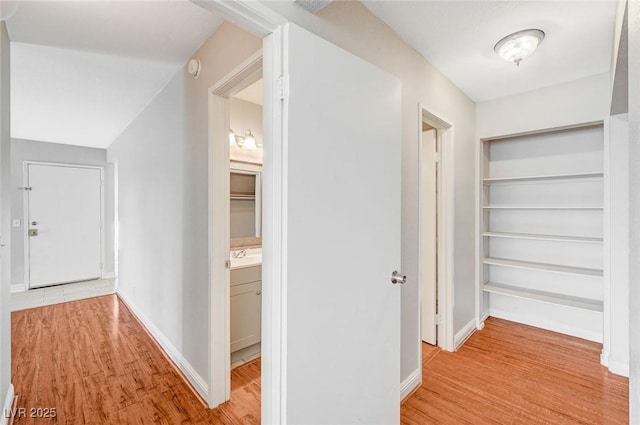 corridor featuring baseboards and light wood finished floors