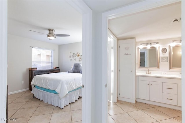 bedroom featuring light tile patterned floors, visible vents, ceiling fan, a sink, and ensuite bath