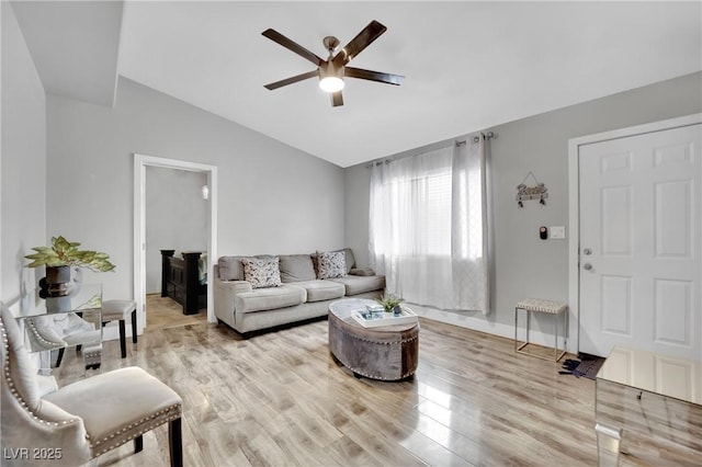 living room featuring light wood finished floors, baseboards, vaulted ceiling, and a ceiling fan