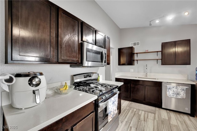 kitchen featuring open shelves, dark brown cabinets, stainless steel appliances, and a sink