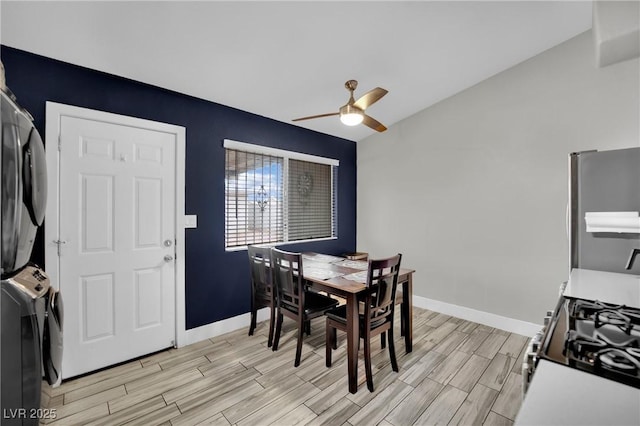 dining space featuring wood finish floors, baseboards, vaulted ceiling, and stacked washing maching and dryer