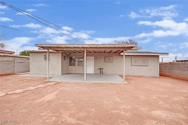 rear view of property featuring fence, a patio, and stucco siding