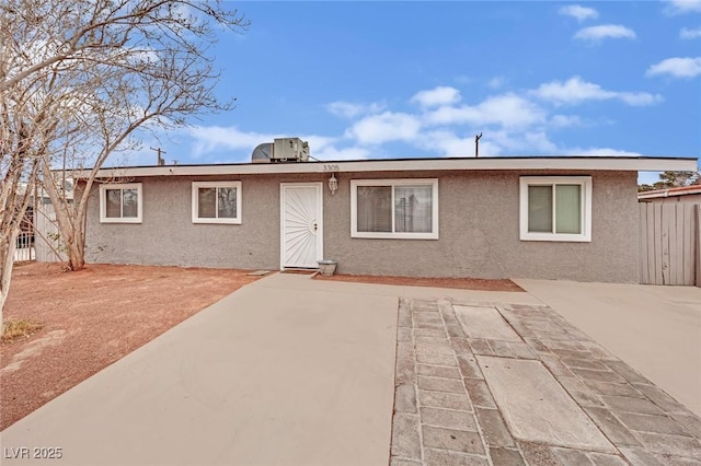 view of front of house featuring a patio area, fence, and stucco siding