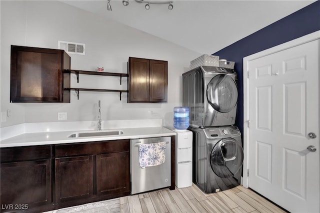 laundry room with laundry area, visible vents, stacked washer / dryer, wood tiled floor, and a sink