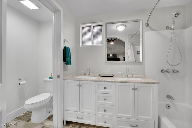 bathroom with toilet, double vanity, bathtub / shower combination, and a sink