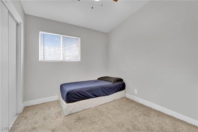 carpeted bedroom featuring lofted ceiling, a closet, baseboards, and a ceiling fan