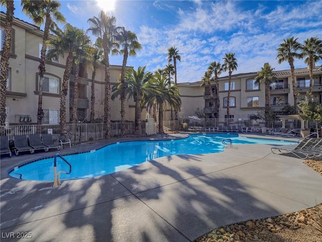 community pool with a patio and fence