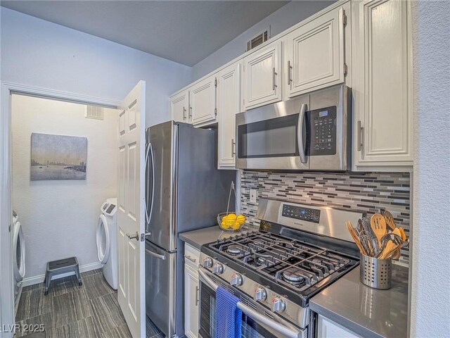 7111 S Durango Dr Unit 305, Las Vegas, NV 89113 - kitchen featuring stainless steel appliances, decorative backsplash, white cabinets, dark countertops, and washer and clothes dryer