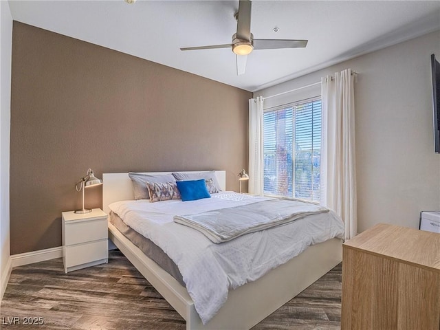 bedroom with ceiling fan, dark wood-type flooring, and baseboards