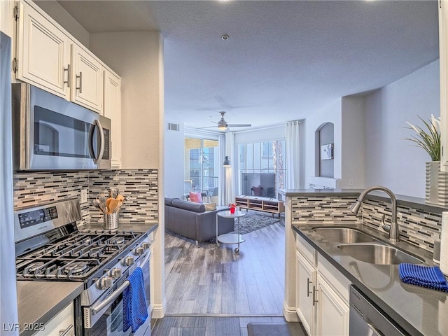 kitchen featuring dark wood-style floors, dark countertops, visible vents, appliances with stainless steel finishes, and a sink