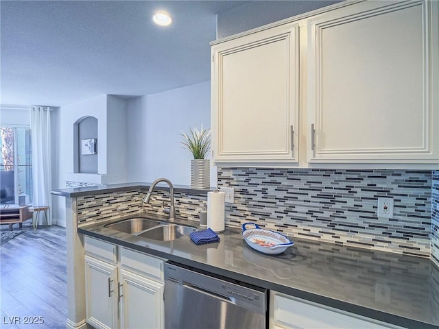 kitchen with tasteful backsplash, dark countertops, a sink, and stainless steel dishwasher