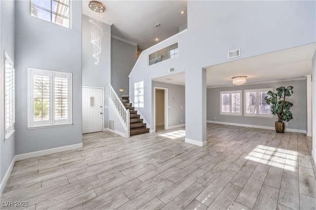 unfurnished living room featuring plenty of natural light, wood finished floors, visible vents, and baseboards