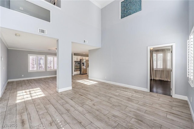 unfurnished living room with light wood finished floors, visible vents, and a wealth of natural light