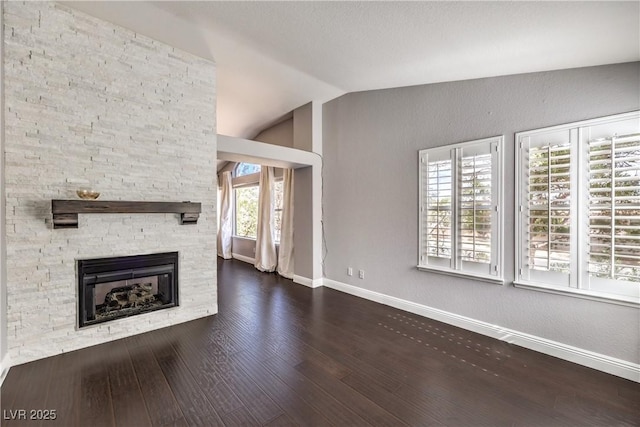 unfurnished living room with lofted ceiling, a fireplace, baseboards, and wood finished floors