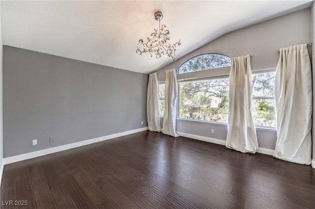 empty room featuring plenty of natural light, vaulted ceiling, and wood finished floors