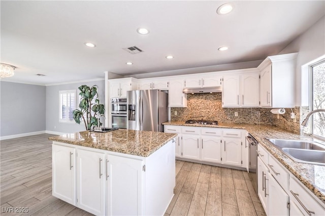 kitchen with visible vents, a center island, stainless steel appliances, under cabinet range hood, and a sink