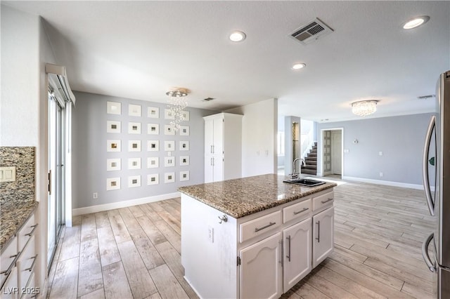 kitchen with light wood-style flooring, a notable chandelier, a sink, visible vents, and freestanding refrigerator