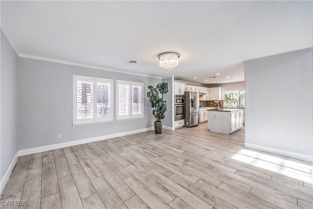 unfurnished living room with visible vents, baseboards, light wood-style flooring, crown molding, and recessed lighting