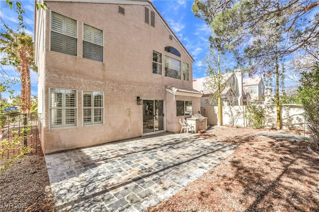 rear view of house featuring a patio area, a fenced backyard, and stucco siding