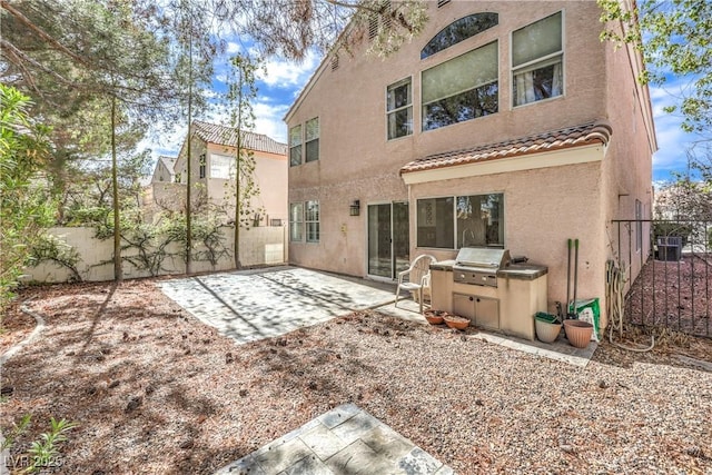 back of house with central AC unit, a tiled roof, fence, a patio area, and stucco siding