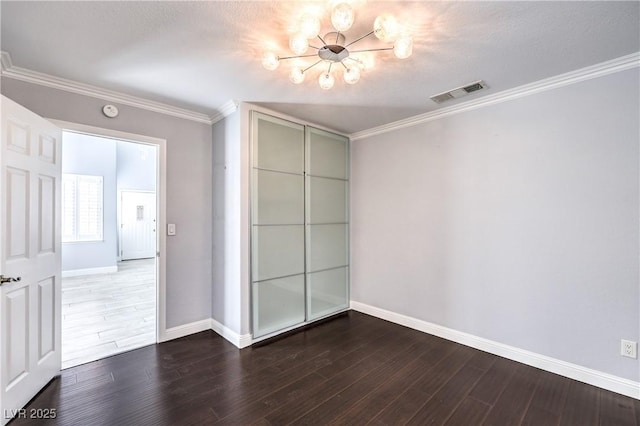 unfurnished bedroom with crown molding, a closet, visible vents, wood finished floors, and baseboards