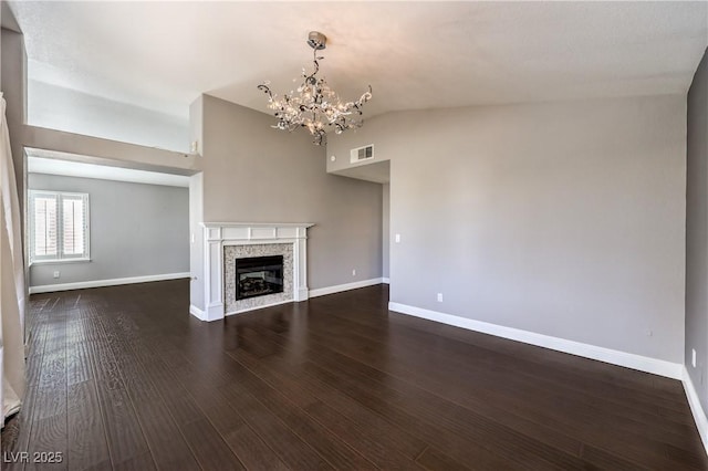 unfurnished living room with lofted ceiling, visible vents, baseboards, dark wood-style floors, and a glass covered fireplace