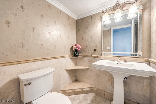 bathroom with toilet, a wainscoted wall, ornamental molding, tile patterned floors, and wallpapered walls