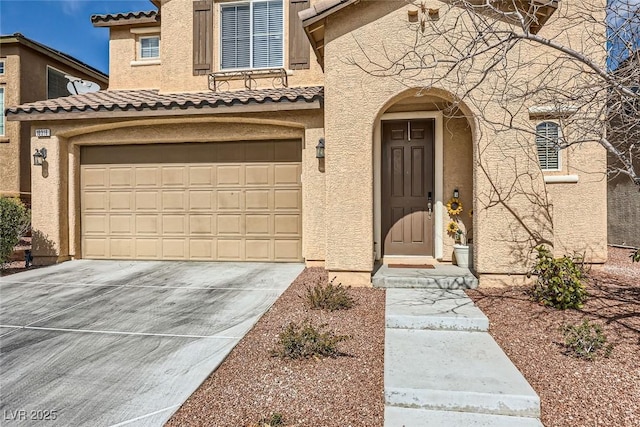 entrance to property featuring a garage, driveway, a tile roof, and stucco siding