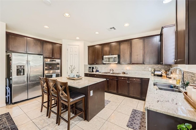 kitchen featuring stainless steel appliances, dark brown cabinets, a sink, and visible vents