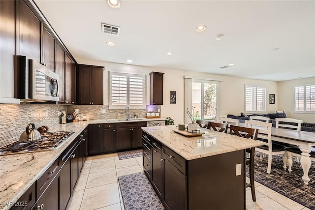 kitchen with visible vents, a breakfast bar area, appliances with stainless steel finishes, open floor plan, and a sink