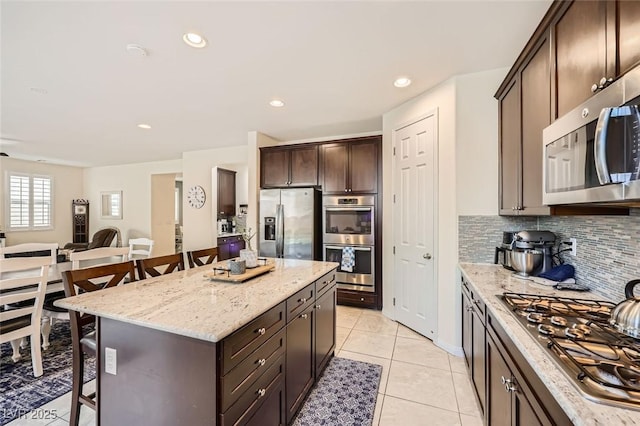 kitchen with appliances with stainless steel finishes, a breakfast bar, decorative backsplash, and open floor plan