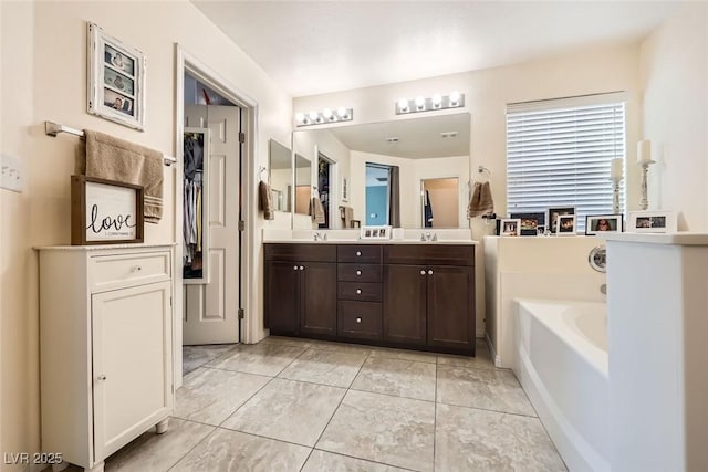 bathroom featuring double vanity, a closet, tile patterned flooring, and a garden tub