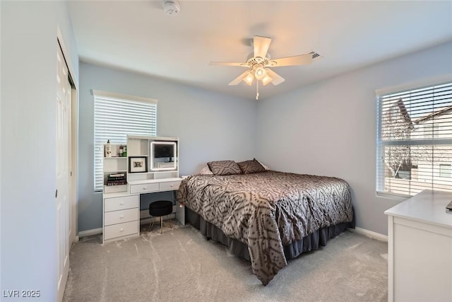 bedroom with a ceiling fan, a closet, light carpet, and baseboards