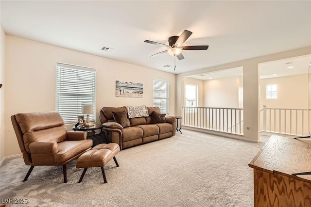 living room featuring light carpet, plenty of natural light, and a ceiling fan