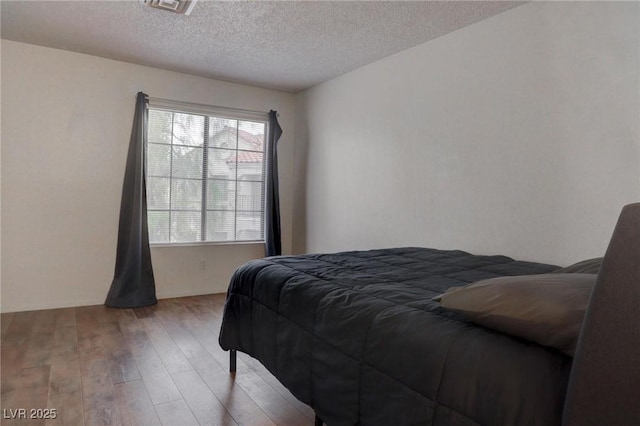 bedroom featuring a textured ceiling and wood finished floors