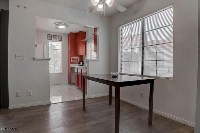 unfurnished dining area with light wood-style floors, ceiling fan, and baseboards