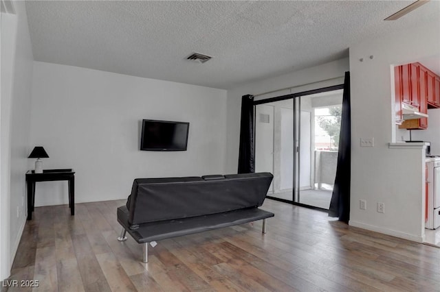 living area featuring light wood-style floors, visible vents, and a textured ceiling