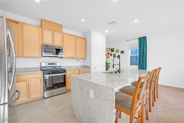 kitchen featuring a sink, visible vents, appliances with stainless steel finishes, and light brown cabinetry