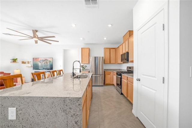 kitchen featuring visible vents, ceiling fan, a large island, stainless steel appliances, and a sink